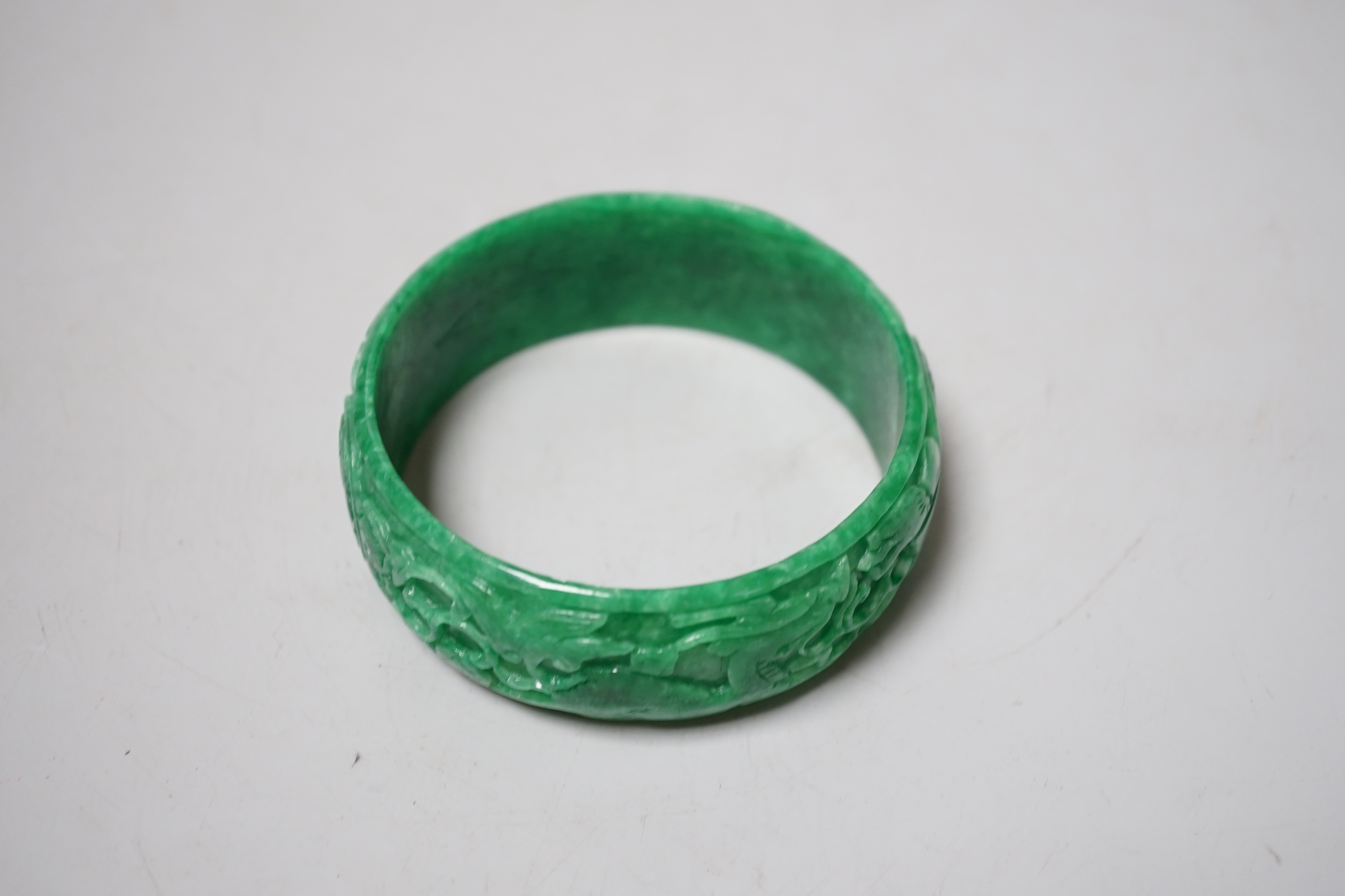 A Chinese carved jadeite bangle, 8.5cm diameter